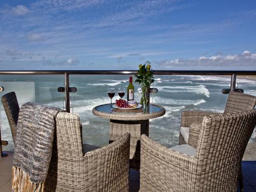 een tafel met wijnglazen op een balkon met uitzicht op de oceaan bij Sunset Bay - 31 Horizon View in Westward Ho