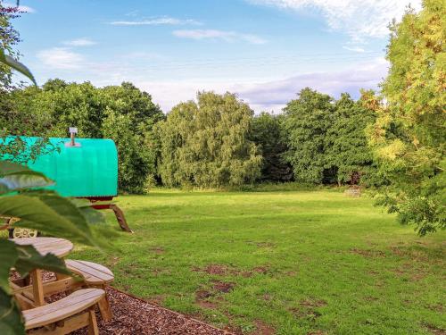a green object sitting in a field with trees at Copperbeech Bowtop in Tilston