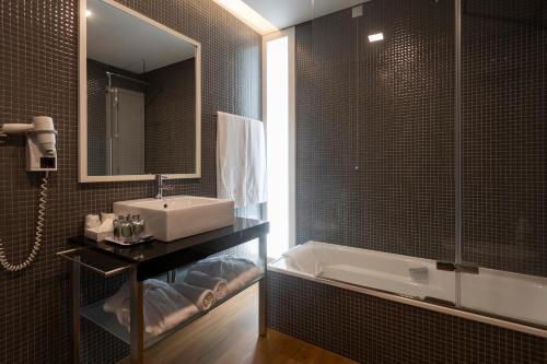a bathroom with a sink and a bath tub at Hotel Flor De Sal in Viana do Castelo