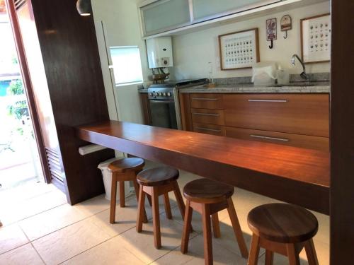 a kitchen with a wooden counter top and stools at Flat 718, Villa hípica, Gravatá in Gravatá