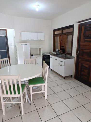 a kitchen with a white table and chairs and a kitchen with a refrigerator at Casa em Itapema in Itapema
