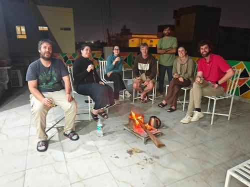 a group of people sitting around a fire at The Pink Nest - Backpackers Abode in Jaipur