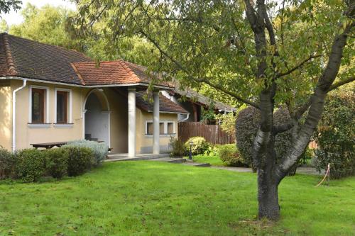 una casa bianca con un albero in un cortile di Erdőparty Vendégház a Tápiószecső