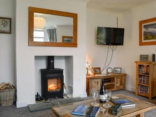a living room with a fireplace and a mirror at Hillside Cottage in Keswick