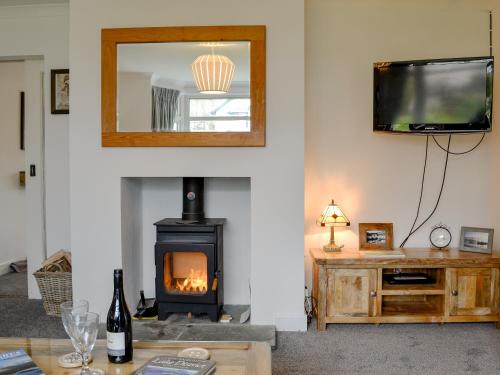 a living room with a wood stove and a tv at Hillside Cottage in Keswick