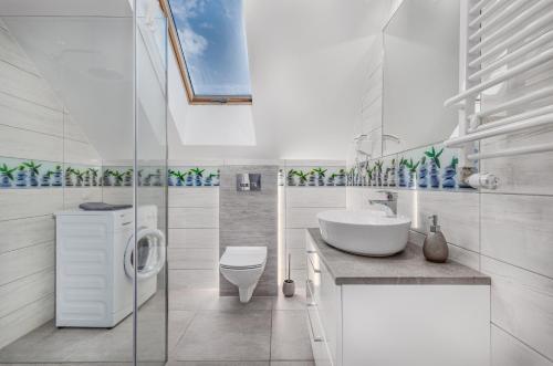 a white bathroom with a sink and a toilet at Domki apartamentowe Na wrzosach in Jastrzębia Góra