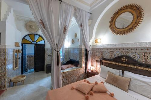 a bedroom with a large bed and a mirror at Riad Arabesque in Marrakech