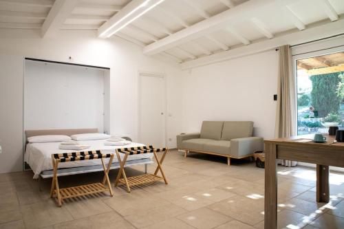 a bedroom with a bed and a couch and a table at Il giardino di Magliano in Magliano in Toscana