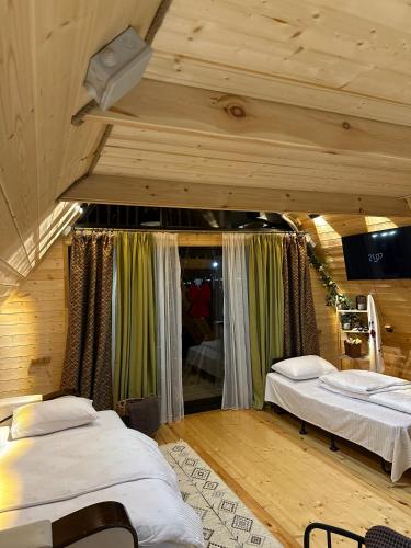 two beds in a room with wooden ceilings at Tasia's Cottage in Tsalka