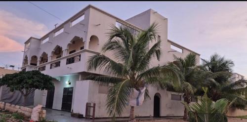 a large white building with palm trees in front of it at Maya, Entire Apartment, Mbour, 3 air-conditioned bedrooms in Mbour