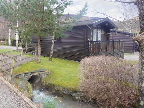 a log cabin with a creek in front of it at Acorn Lodge - Burnside Park in Keswick