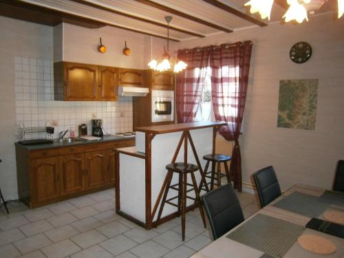 una cocina con armarios de madera, mesa y sillas en Gite Au Nid De Cigognes, en Dieffenthal