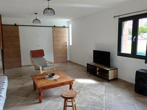 un soggiorno con un divano, un tavolo e una TV di Le gîte Normand a Saint-Vaast-dʼÉquiqueville