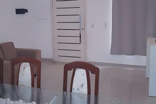 a dining room with two chairs and a glass table at Sobrado 2 amplo e confortável em condomínio in Corumbá