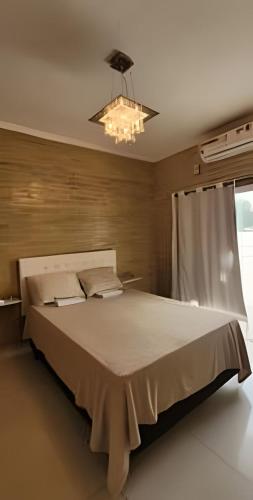 a large bed in a bedroom with a chandelier at Sobrado 2 amplo e confortável em condomínio in Corumbá