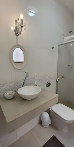 a bathroom with a sink and a toilet and a mirror at Sobrado 2 amplo e confortável em condomínio in Corumbá