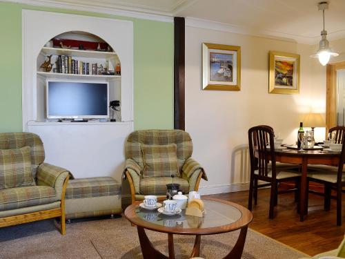 ein Wohnzimmer mit Stühlen und einem Tisch und einem Fernseher in der Unterkunft Boatmans Cottage - 27787 in Portessie