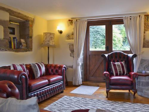 a living room with a leather couch and two chairs at Swallows Loft in Cromford