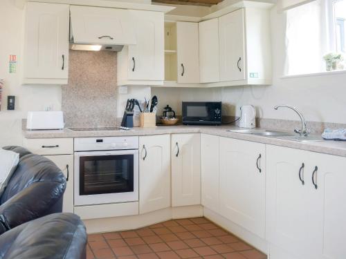 a kitchen with white cabinets and a sink at The Parlour - Uk6717 in Lydstep