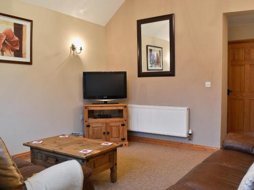 a living room with a tv and a coffee table at Shippon Cottage - E4299A in Halston