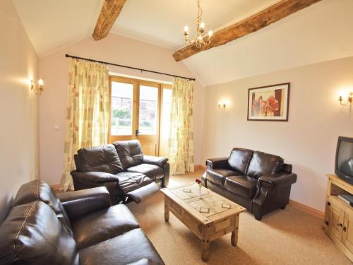 a living room with leather furniture and a tv at Shippon Cottage - E4299A in Halston