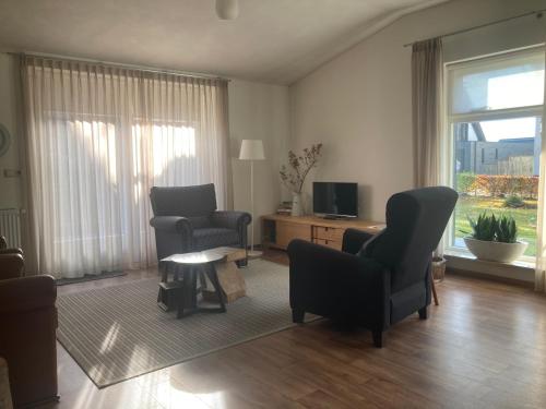 ein Wohnzimmer mit zwei Stühlen und einem Fernseher in der Unterkunft Bungalow Buitenlui in Molenschot