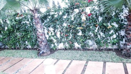 a fence covered in ivy with flowers on it at Villa de luxe CGI avec piscine in Bouskoura