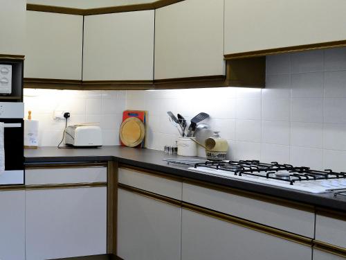 a kitchen with white cabinets and a stove top oven at Belgravia Cottage in Skipton