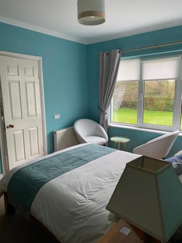 a blue bedroom with a bed and a window at Ocean Lodge B&B in Renvyle