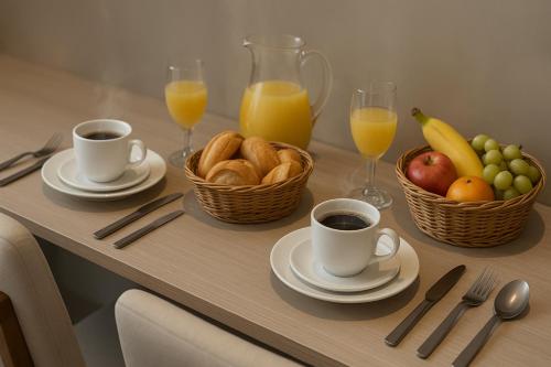 a table with a breakfast of fruit and coffee and juice at Bahia Flats Facility View in Salvador