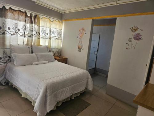 a bedroom with a white bed and a window at TURFLOOP guest house in Mankweng