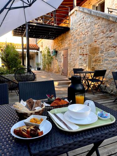 una mesa con platos de comida y una sombrilla en Gîtes de la chocolaterie, en Viré