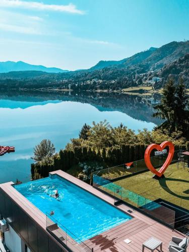 a swimming pool with a heart sign next to a lake at Hotel Roser House Boutique - pe malul lacului Colibita in Colibiţa