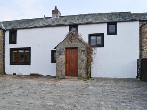 un bâtiment blanc avec une porte rouge dans une rue dans l'établissement Greenrigg Cottage, à Caldbeck