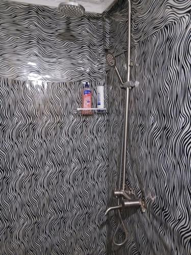 a bathroom with a black and white patterned wall at Patience Airport cottages in Boma la Ngombe