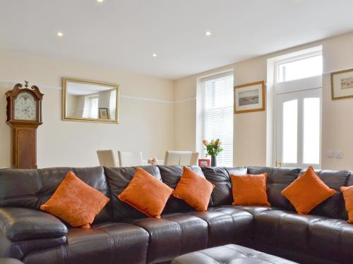 een zwarte leren bank met oranje kussens in de woonkamer bij Hedderwick House in Pittenweem