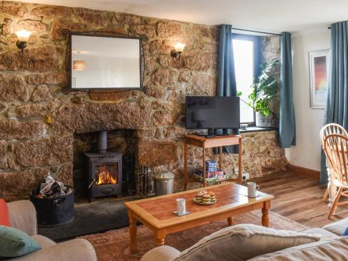 a living room with a stone wall with a fireplace at Bishop Rock - Grl in Trevilley