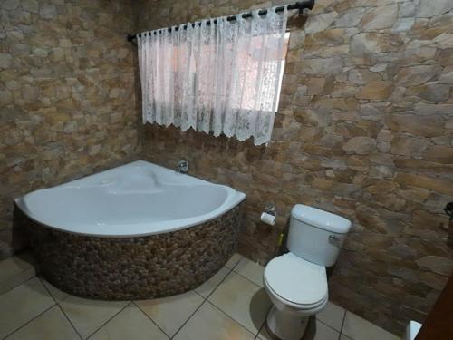 a bathroom with a bath tub and a toilet at Evergreen guest house in Pietermaritzburg
