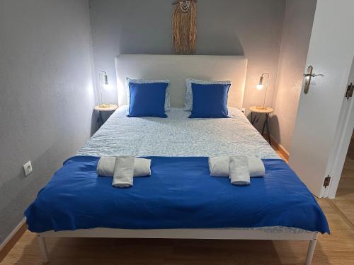 a blue bed with blue pillows and two towels on it at Casinha de Galveias in Galveias