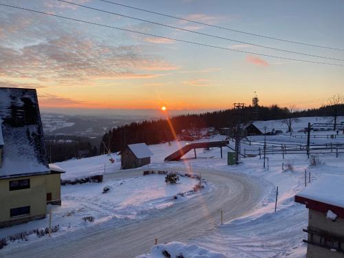 a road in the snow with the sunset in the background at Chaloupka Příchovice in Kořenov
