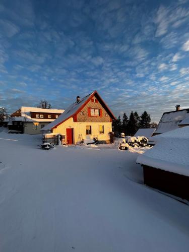a house with snow on the ground next to buildings at Chaloupka Příchovice in Kořenov