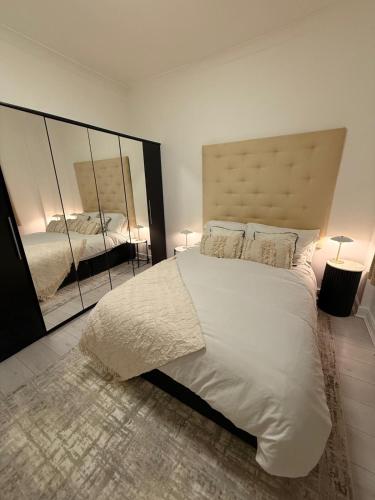 a bedroom with a large white bed and a mirror at The Stanhope - Ground Floor Apartment in Frecheville