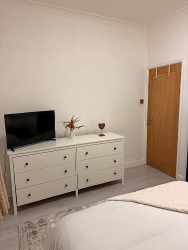 a bedroom with a white dresser with a television on it at The Stanhope - Ground Floor Apartment in Frecheville