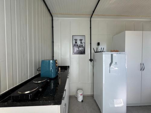 a kitchen with a black counter and a white refrigerator at Charmoso e bem localizado! in Tijucas
