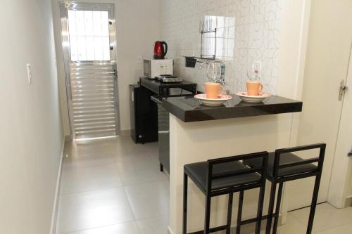 eine Küche mit einer Theke mit 2 Stühlen und einem Herd in der Unterkunft Apartamento novo com ar condicionado e garagem in São Lourenço