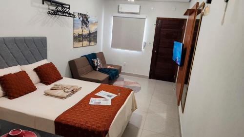 ein Schlafzimmer mit einem Bett und einem Stuhl und einem Fernseher in der Unterkunft Apartamento novo com ar condicionado e garagem in São Lourenço