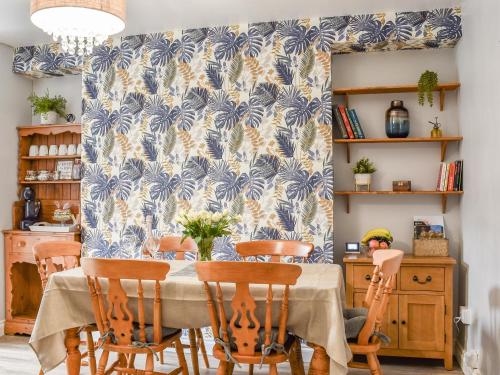 a dining room with a table and chairs with a blue and white wallpaper at Cwmcarn Cottage in Crosskeys