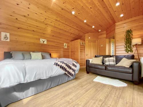 a bedroom with a bed and a leather couch at Apple-Uk46285 in Camerton