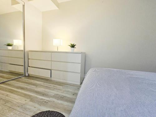 a white bedroom with a bed and a mirror at Garden Ave Suite 3 Mins to Hwy 403 in Brantford