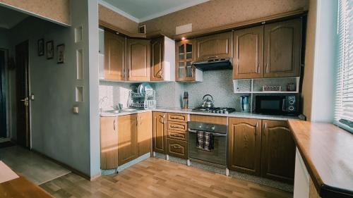 a kitchen with wooden cabinets and a stove top oven at Олександрійський б-р 125 CityRooms in Bila Tserkva